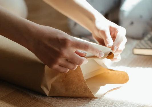 pakowanie paczki w szary papier z taśmą klejącą w tle