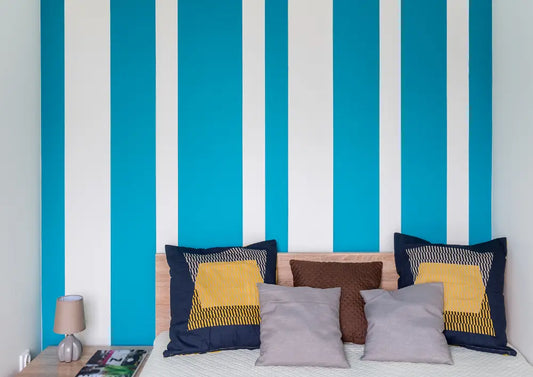 sypialnia pomalowana w niebiesko białe pasy na ścianie